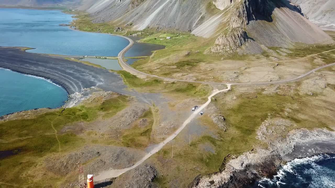 Stunning view of Hvalnes in Iceland, showcasing dramatic coastal mountains, serene blue waters, rugged terrain, and winding roads. A breathtaking blend of nature’s raw beauty and tranquility