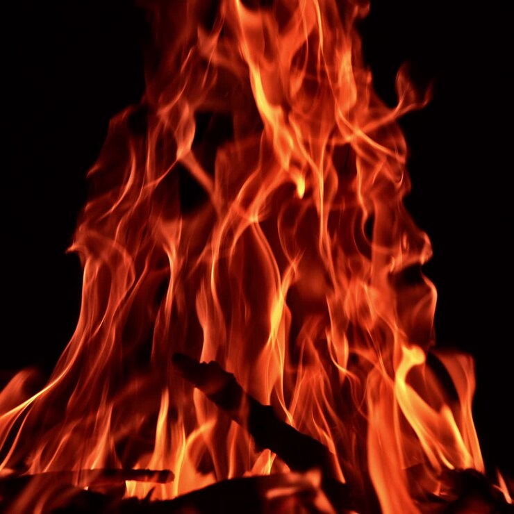 Grande falò acceso di notte. Bastoni neri bruciano nel braciere con una fiamma rossa. Primo piano