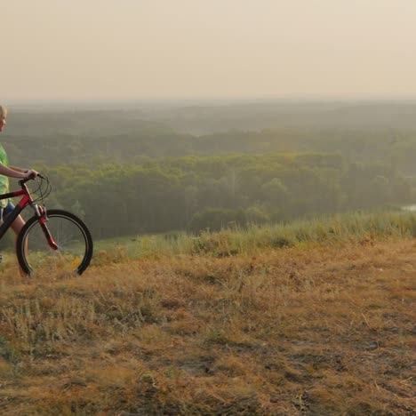 una mujer con una bicicleta camina al atardecer