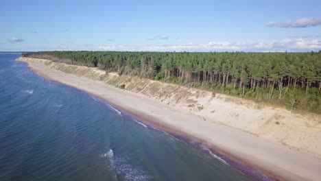 Luftaufnahme-Des-Ostseestrandes-In-Jurkalne-An-Einem-Sonnigen-Tag,-Weiße-Sandklippe-Beschädigt-Durch-Wellen,-Küstenerosion,-Klimaveränderungen,-Weitwinkel-drohnenschuss,-Der-Sich-Hoch-Nach-Vorne-Bewegt-1