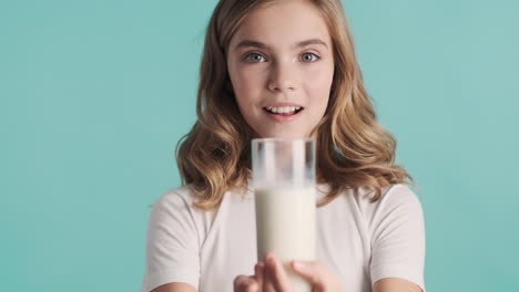 Teenage-Caucasian-girl-in-pijamas-holding-a-glass-of-milk-and-smiling.