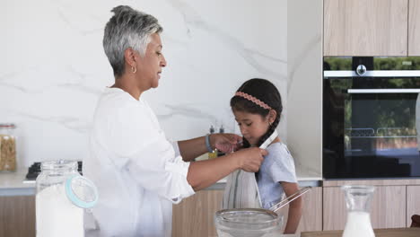 Biracial-man-assists-a-biracial-girl-with-cooking-in-a-modern-kitchen