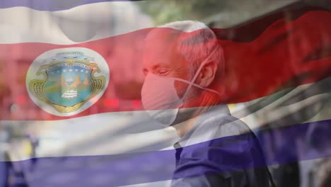 animation of flag of costa rica waving over caucasian man wearing face mask in city street