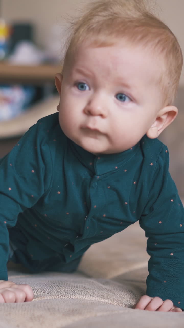 adorable little boy with bright blue eyes learns to crawl on large beige bed in spacious room at home