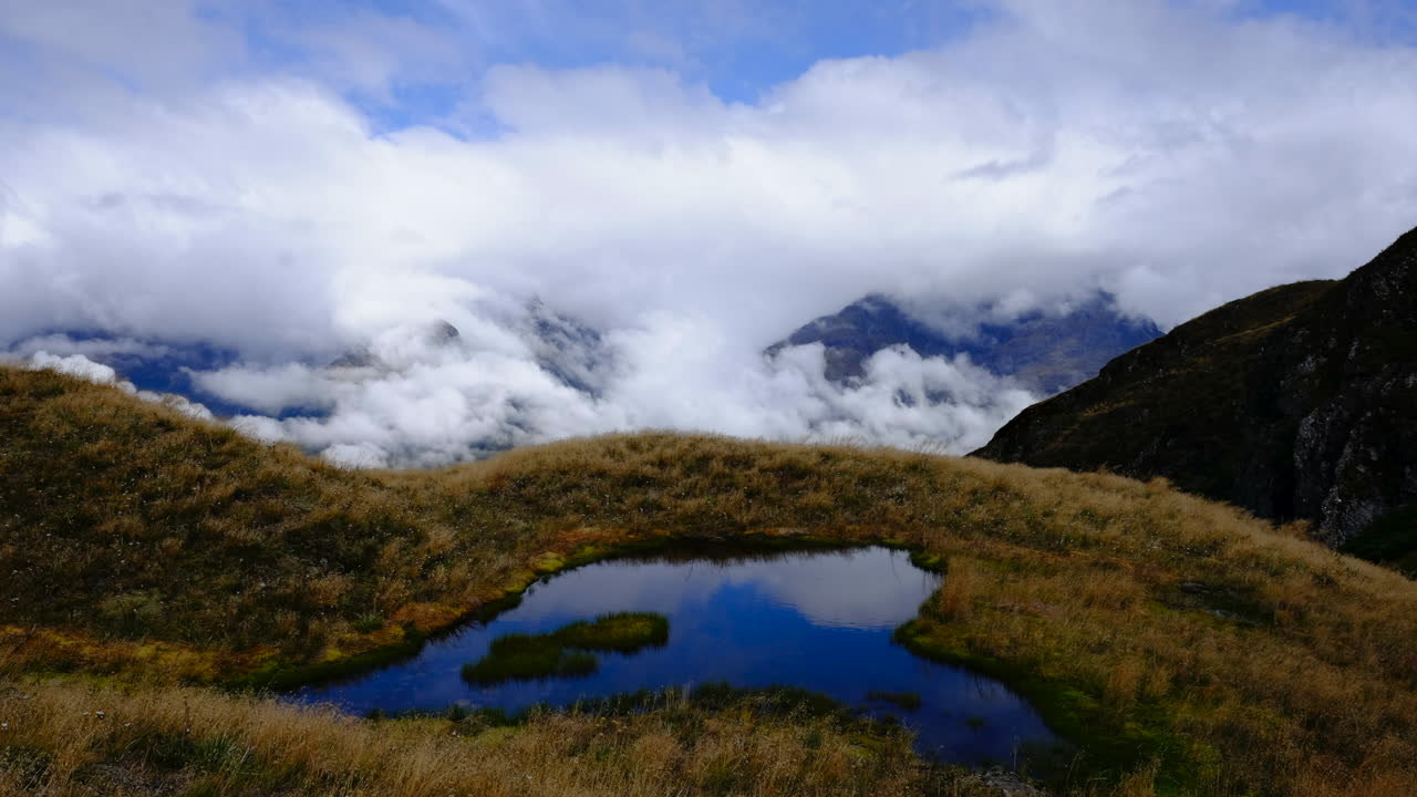 lapso de tiempo de nubes en las montañas de nueva zelanda con tarn reflectante