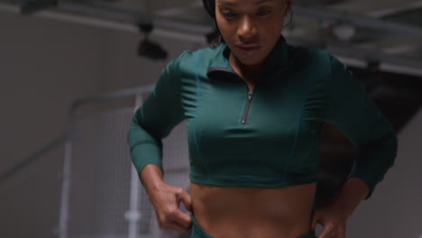 portrait of determined female athlete wearing tracksuit training in gym stretching and warming up preparing for sports event 1