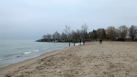 People-enjoying-overcast-Christmas-day-at-the-beach-at-Scarborough-Bluffs,-Toronto,-Canada