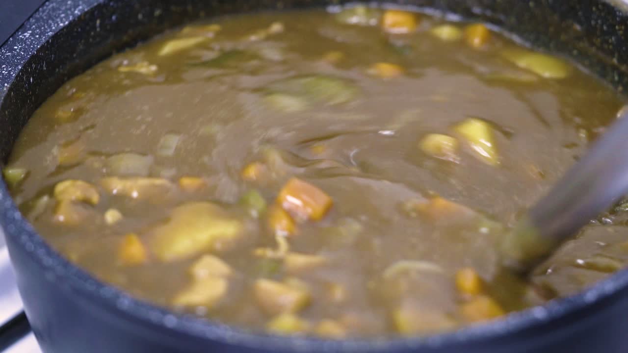 cierre la cocina de curry japonés en una olla antiadherente, usando un cucharón de silicona revuelva el curry japonés para verificar el estado de la comida, vista desde arriba
