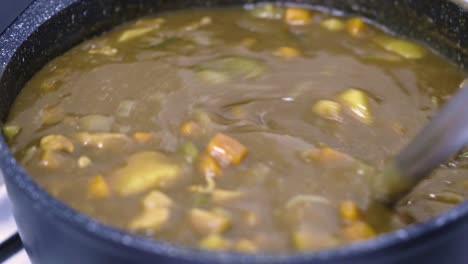 Close-up-cooking-Japanese-curry-in-a-non-stick-pot,-using-a-silicone-ladle-stir-the-Japanese-curry-to-check-the-status-of-the-food,-view-from-above