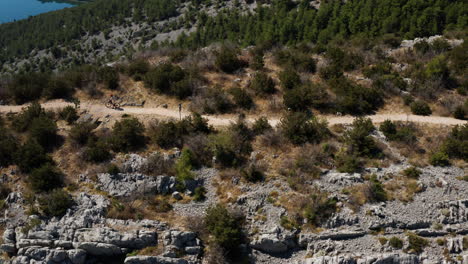 Two-People-Riding-A-Bicycle-Traveling-Near-The-Edge-Of-Mountains-In-Krka-National-Park,-Croatia