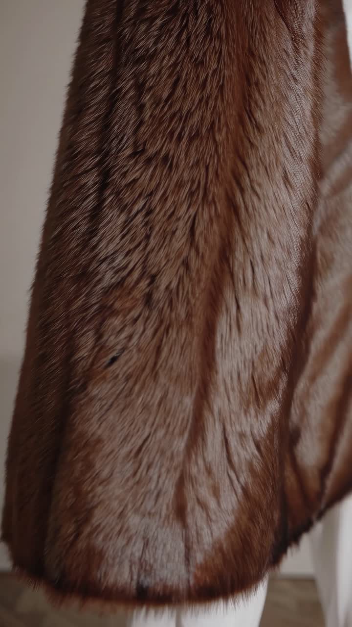 Close-up video shot of a luxurious brown fur coat, capturing rich textures and details from a side