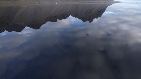 Tiro-Inclinado-Hacia-Arriba-Del-Reflejo-De-La-Montaña-Vestrahorn-En-La-Superficie-Del-Agua-Durante-El-Día,-Islandia