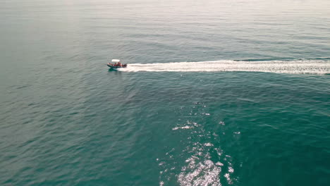 Barco-Moviéndose-A-Alta-Velocidad-En-El-Mar,-Una-Larga-Estela-Sigue-Al-Barco-En-Cerdeña,-Italia-Durante-El-Verano---Tiro-Estático-Aéreo