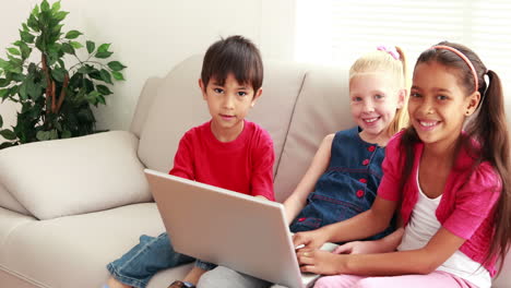 Drei-Süße-Kinder,-Die-Zusammen-Einen-Laptop-Auf-Dem-Sofa-Benutzen