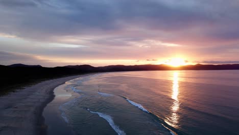 colorful sunset over water surface in spirits bay, new zealand - aerial drone shot