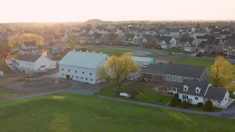 Aerial-of-Amish-farm-and-homestead-surrounded-by-new-luxury-home-development-neighborhood-in-Pennsylvania-USA