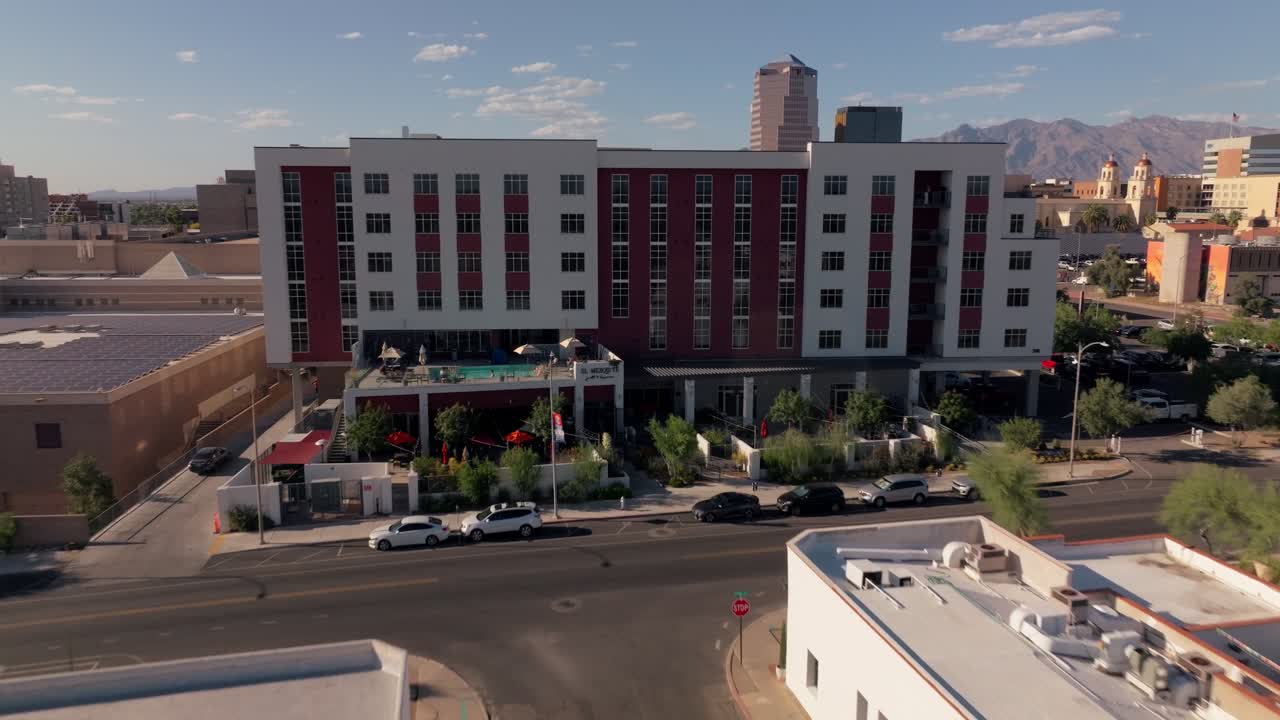 Aerial view of a modern hotel and surrounding city with mountains in the background