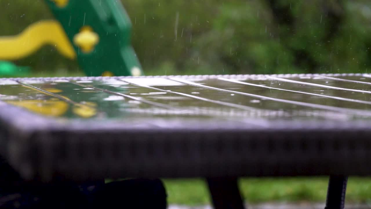 imágenes de una fuerte lluvia con muchas gotas de lluvia aterrizando en una mesa húmeda en cámara lenta