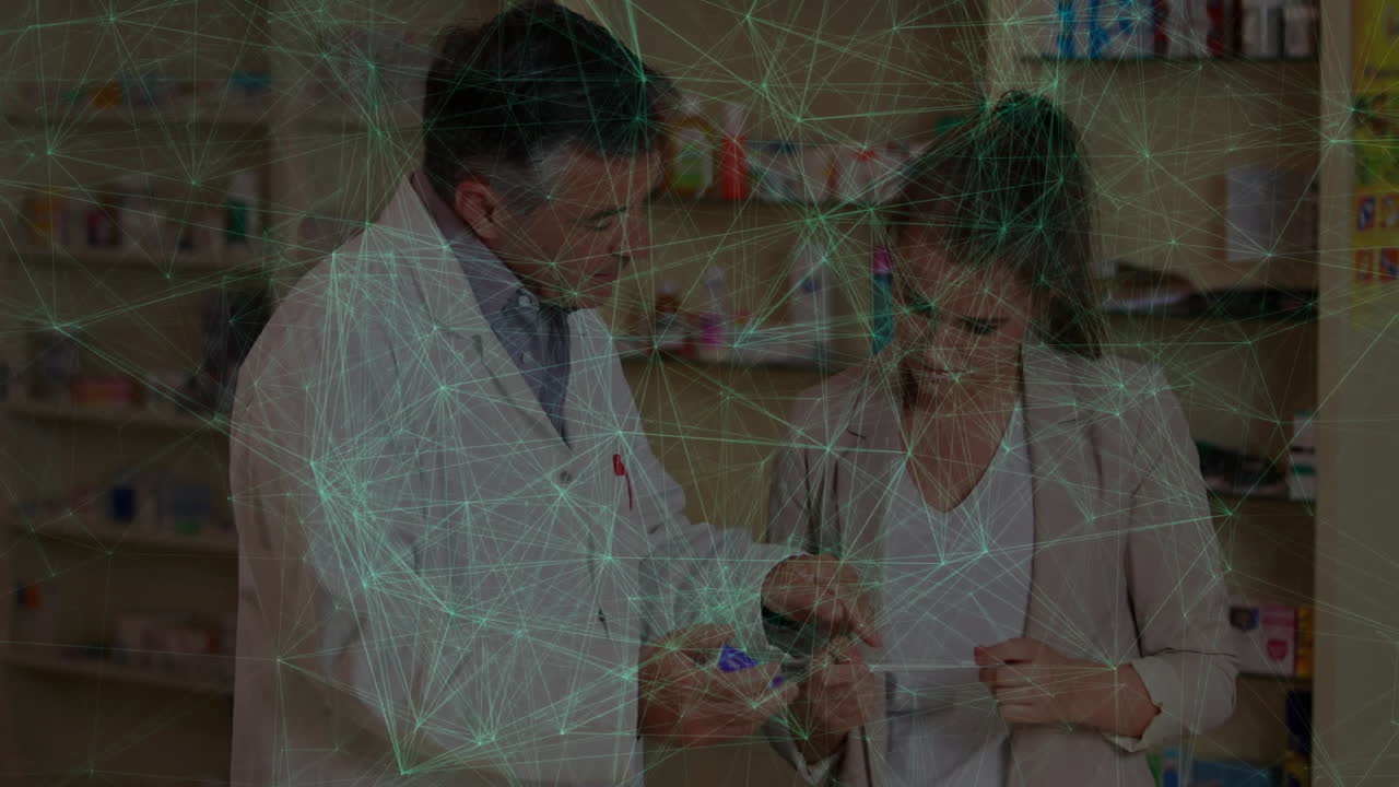 Mature male pharmacist showing medication box to customer in pharmacy, with green node overlay