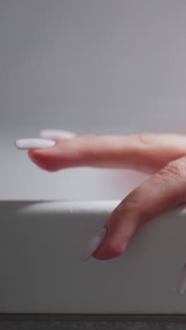 woman taps finger on bathtub edge at home closeup. relaxed lady enjoys taking hot bath in hotel washroom. woman washes body and recreates in tub