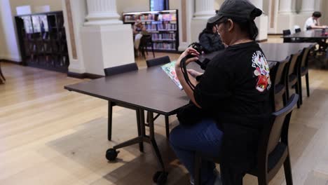 woman reading book at library table