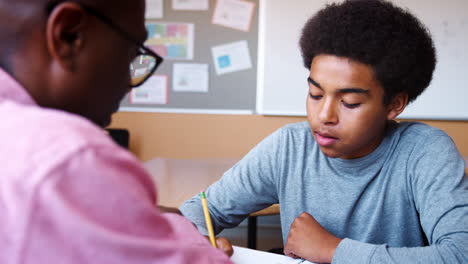 tutor de escuela secundaria dando a los estudiantes varones una a una enseñanza en el escritorio