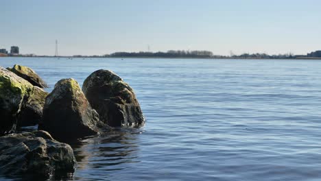 Close-up-shot-of-a-rocky-lake-shore-with-a-gentle-breeze-on-the-water