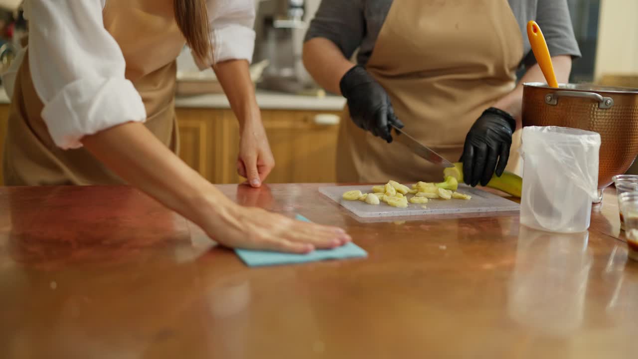 두 사람이 부에서 음식을 준비하고, 한 명이 바나나를 고 있습니다.