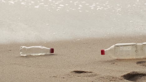 Zwei-Plastikflaschen-Mit-Getränken-Liegen-Am-Strand-Zurück.