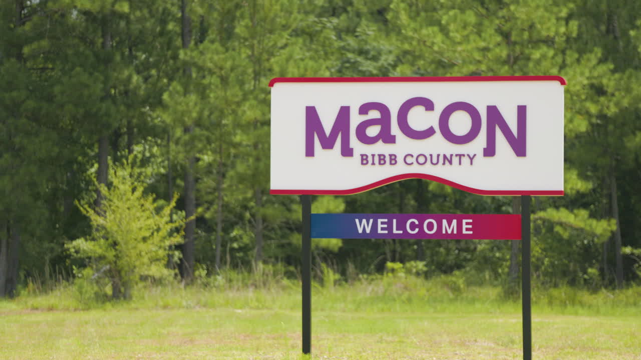 condado de macon bibb georgia bienvenida cartel de carretera en frente de los bosques telefoto pan izquierda 60p 0002