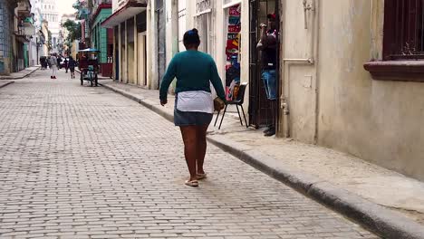 slow motion forward dolly shot behind a local woman walking in the street of la havana, cuba