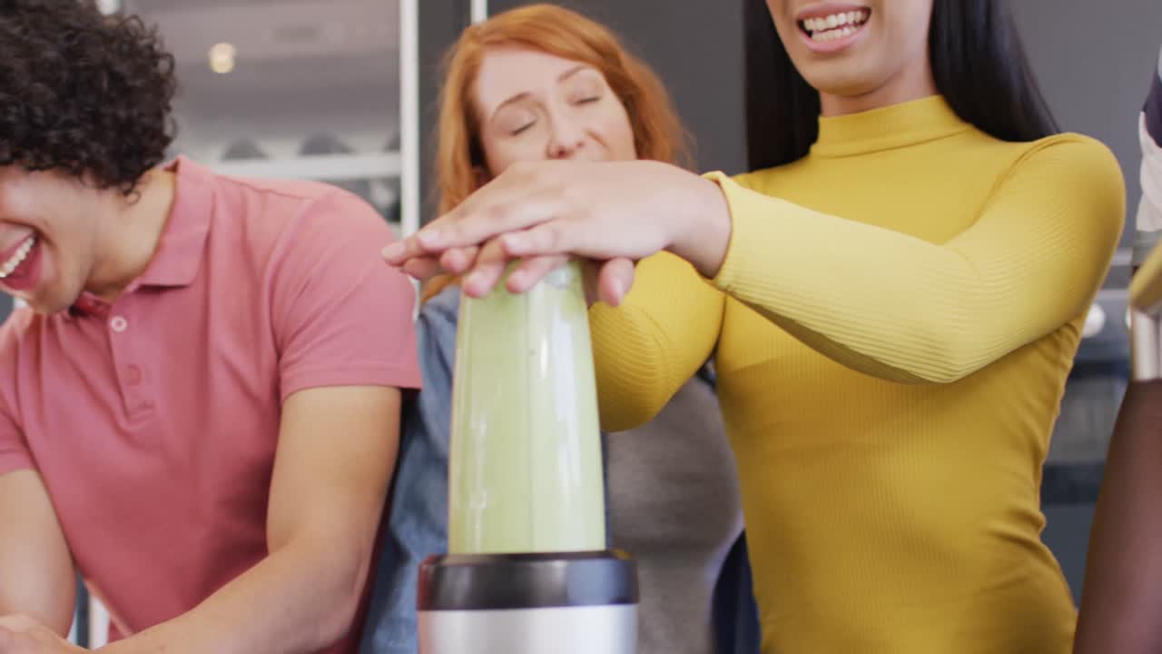un grupo feliz de amigos diversos preparando una bebida saludable en la cocina juntos