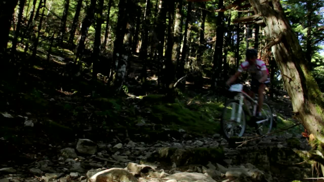 A cyclist quickly passing by the camera in a forest path for a mountain bike marathon in Tzoumerka in Greece