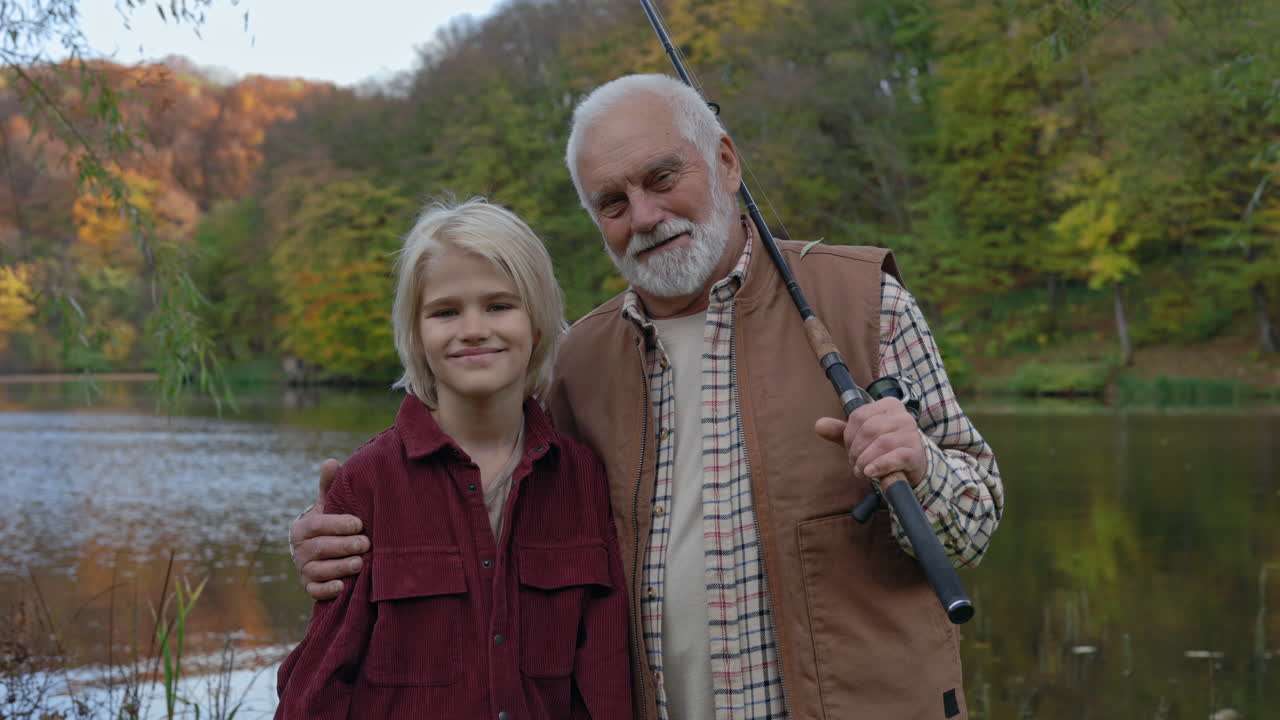 Grand-père et petit-fils profitant d'une partie de pêche au bord du lac en automne.