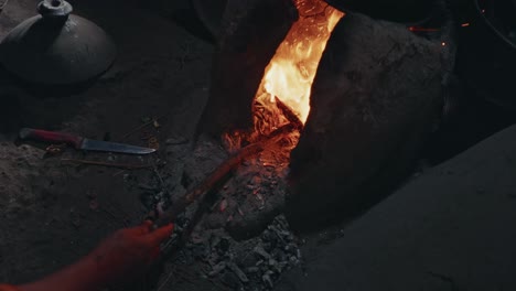 close up shot of a moroccan woman at a fireplace baking traditional bread inside clay made house at a rural village in the atlas mountains.