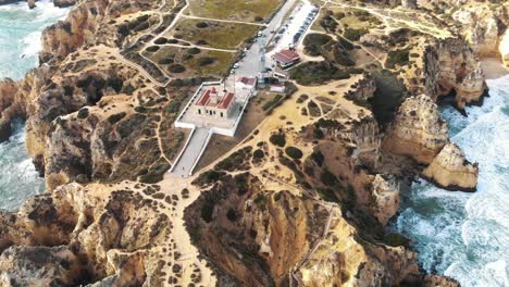 Ponta-da-Piedade-Lighthouse,-cliff-formations-along-coastline-of-Lagos,-Algarve,-Portugal