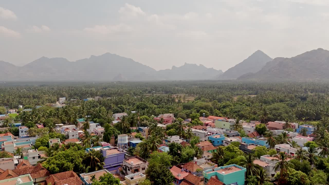 Aerial shot of suburb cityscape with mountains at background during daytime. Foggy landscape.