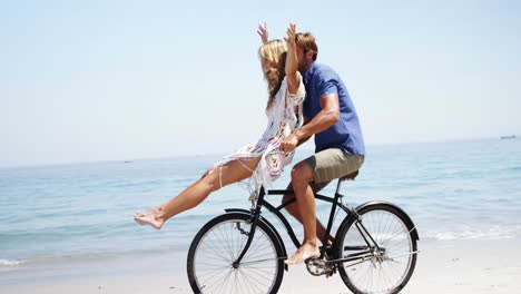 happy couple riding bicycle at beach