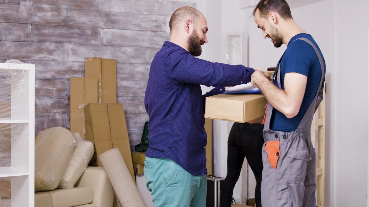 Man Receiving a Package from a Delivery Person in a New Apartment