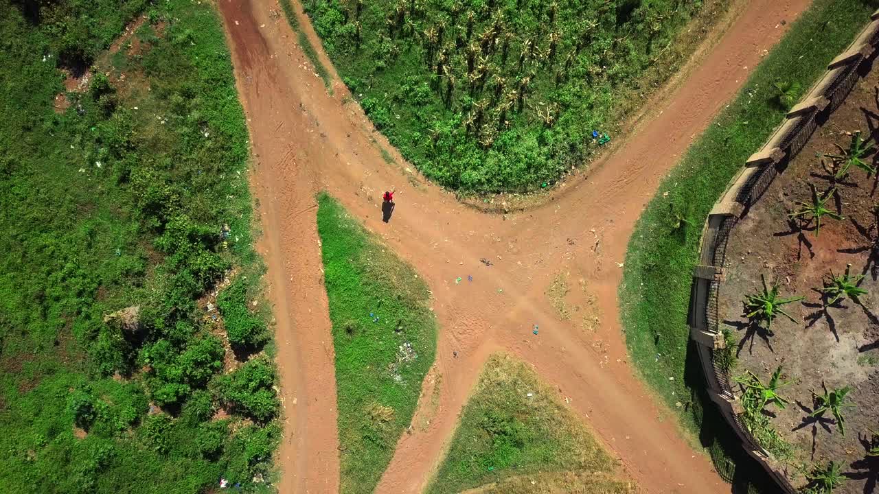 Top Down View Of A Girl Walking Through A Village To Collect Water In A Jerrycan In Africa. - aerial shot