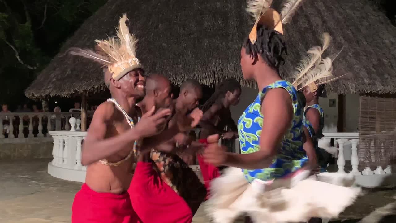 Traditional African dancers enjoying dance performance, smiling and enjoying pair - couple dance. Ethnic cultural dancing performed by black dancers at Kenyan lodge - hotel.