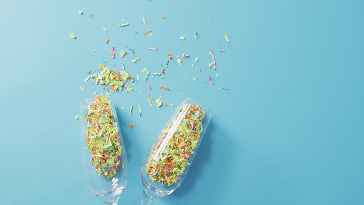 Champagne glasses with confetti on blue background at new year's eve