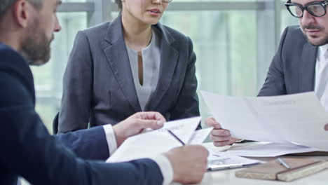 meeting of business people sitting at a table while looking at documents