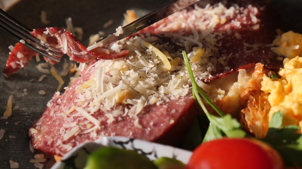 Person Cutting a Gourmet Breakfast Dish with Salami and Cheese