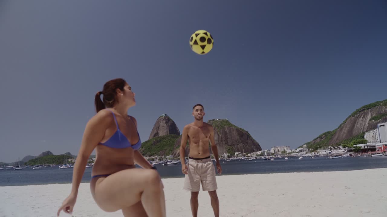 Young adults playing footvolley on a sunny beach in Rio de Janeiro