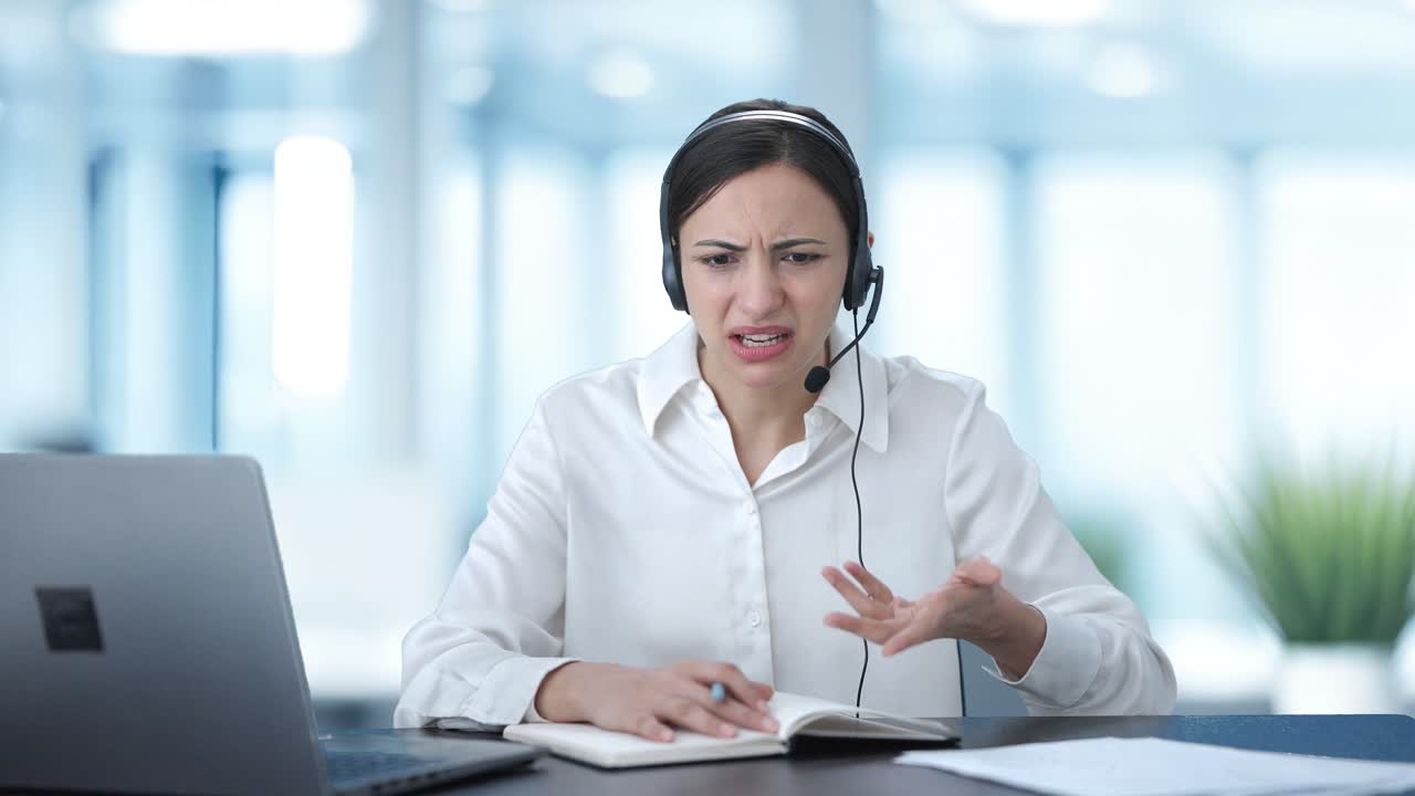 Confused Indian call center girl talking to customer and taking notes