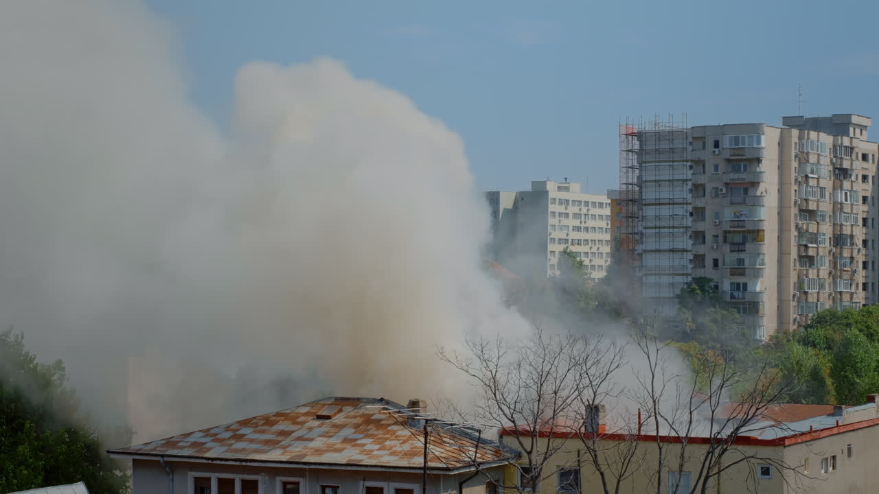 View of flames getting out of burning house in city landscape