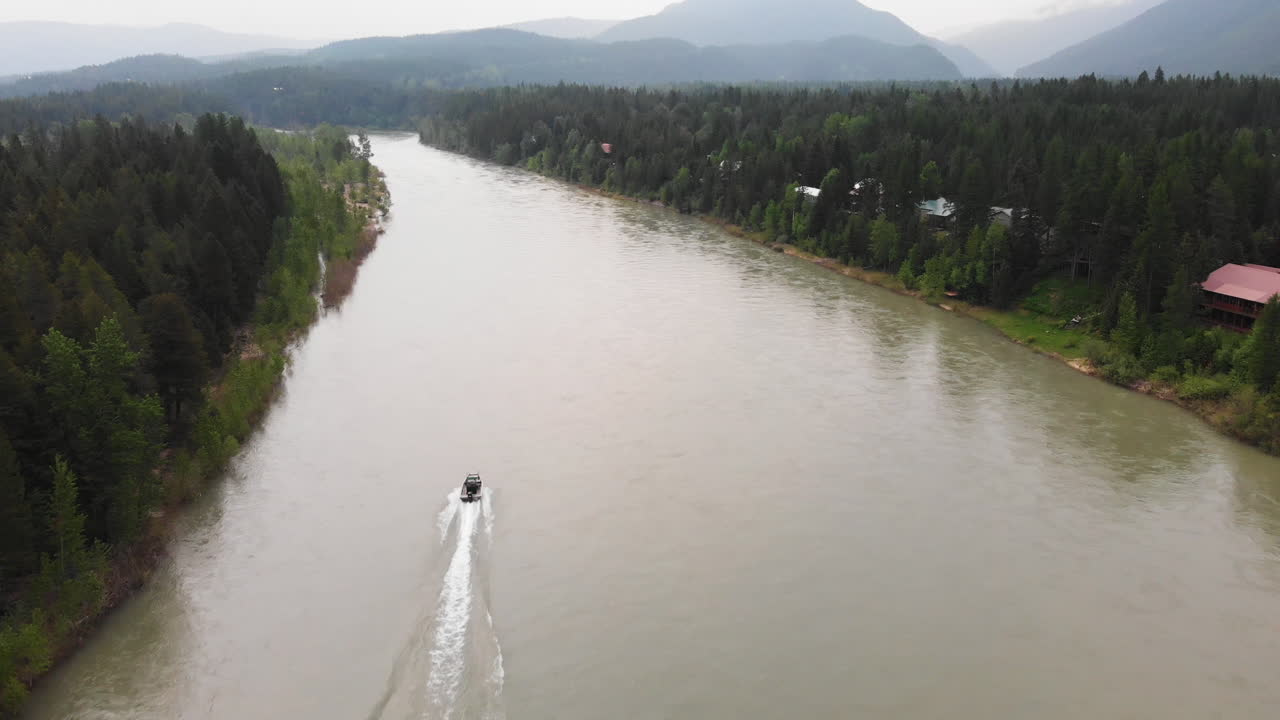 съемка с воздуха лодки, несущейся по реке флэтхед, камера поднимается вверх, показывая горы, покрытые дымом от близлежащего лесного пожара