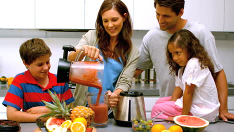 Frau-Mit-Familie-Gießt-Fruchtcocktail-Aus-Einem-Mixer