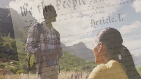 Animation-of-american-flag-over-smiling-diverse-couple-hiking-in-mountains